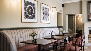 A restaurant with a long bench seating area, tables, and chairs. - Methuen Arms (Corsham)