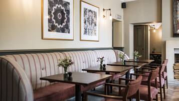 A restaurant with a long bench seating area, tables, and chairs.
