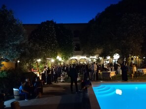 Ein Außenbereich mit Pool, umgeben von Bäumen und einem Gebäude mit Bögen.