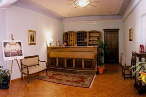 Une pièce comprenant un banc en bois, un bureau debout, une plante en pot et un tableau encadré accroché au mur.