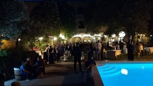 An outdoor gathering area with a pool, surrounded by trees and a building with arches. - Hotel Funtana Noa (Villanovaforru)