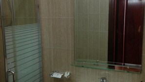 A bathroom with a glass shower enclosure, a glass shelf, and a mirror. - Arvi (Durrës)