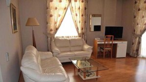 A living room with a sofa, a coffee table, a desk, and a television. - Arvi (Durrës)