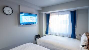 Habitación de hotel con dos camas, un reloj de pared, una pantalla digital y una ventana con cortinas.