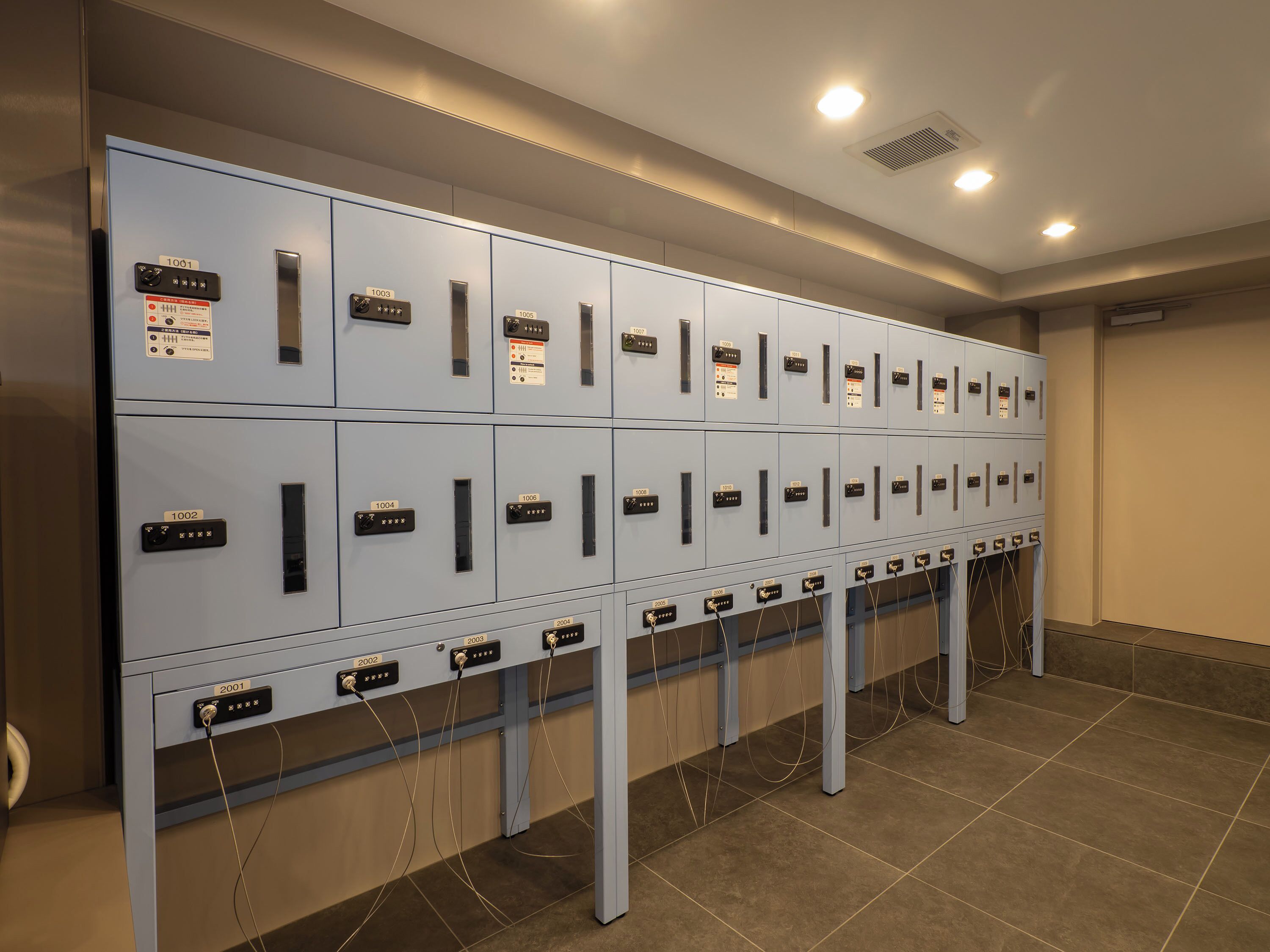 A row of grey lockers with numbered labels, likely for storage or security purposes.