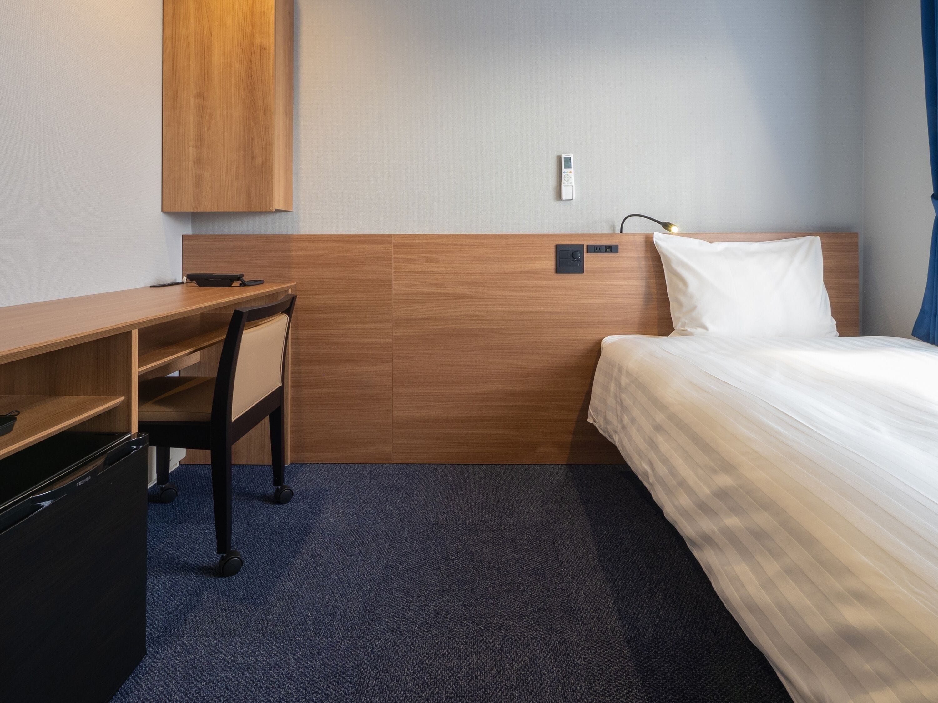 A hotel room with a bed, a desk, and a chair.