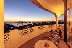 A balcony with a view of a cityscape and water at dusk.