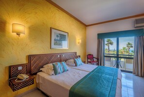 A hotel room with a large bed, two bedside tables, a nightstand, a chair, and a balcony with a view. - Casabela (Lagoa)