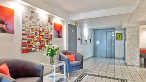 En moderne lobby med to sofaer, et sofabord og et mønstret tæppe.