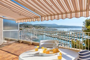 A balcony with a view of a marina, a table with drinks, and a bottle. - Résidence Pierre & Vacances Bandol Port (Bandol)