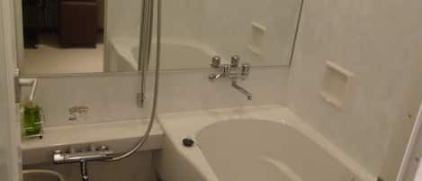 A bathroom with a bathtub, a shower, a sink, and a mirror.
