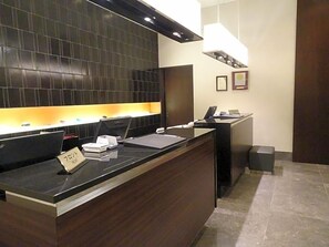 A reception desk with a computer, phone, and a sign indicating 'Room'. - Hotel Toyota Castle (Toyota)