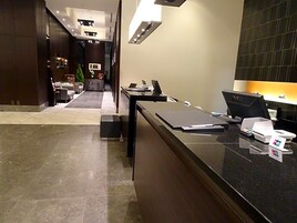 Un moderno vestíbulo de hotel con mostrador de recepción, área de estar y vista al interior.
