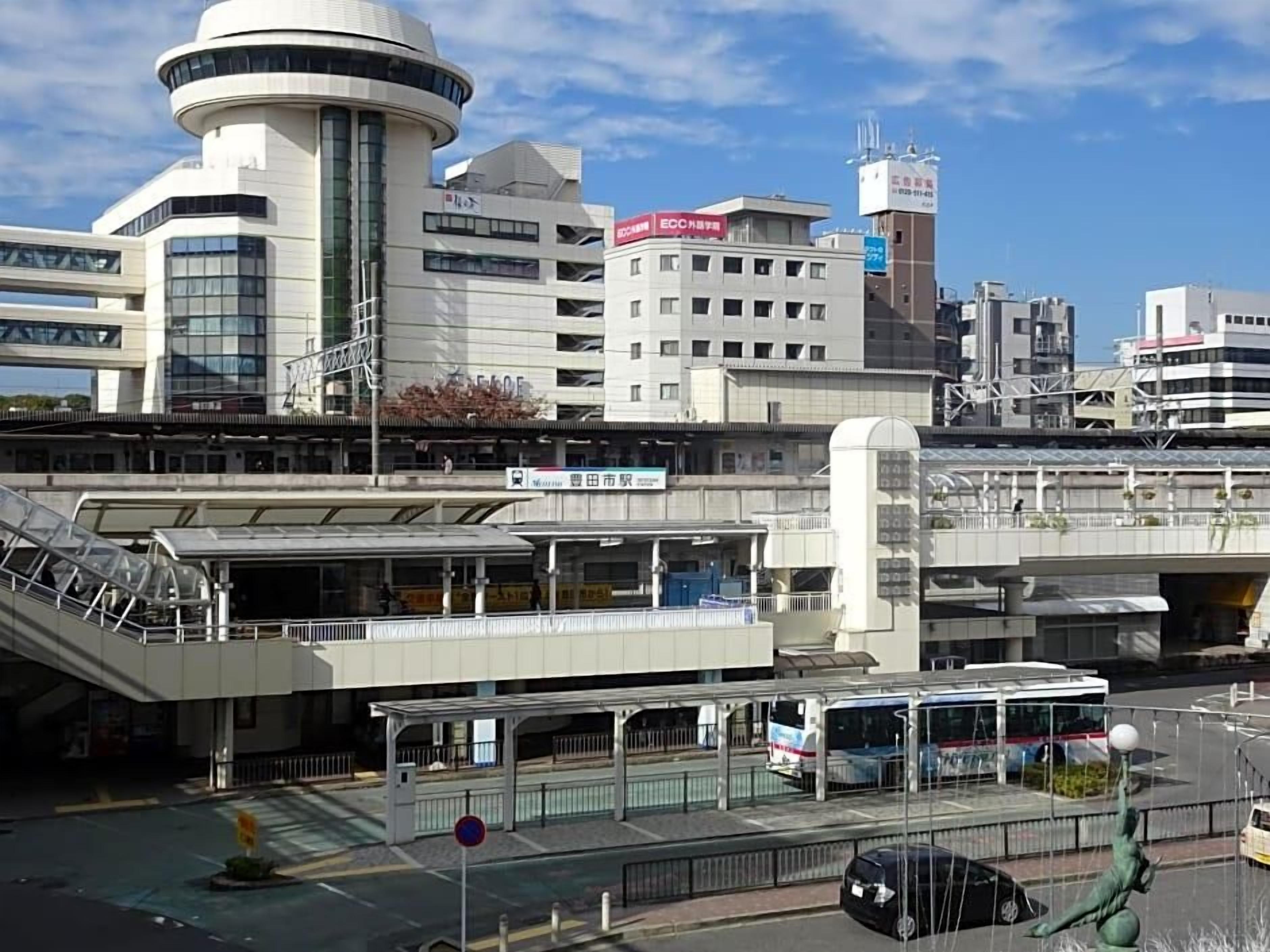 A modern building with a circular tower, a covered pedestrian walkway, and a bus stop.