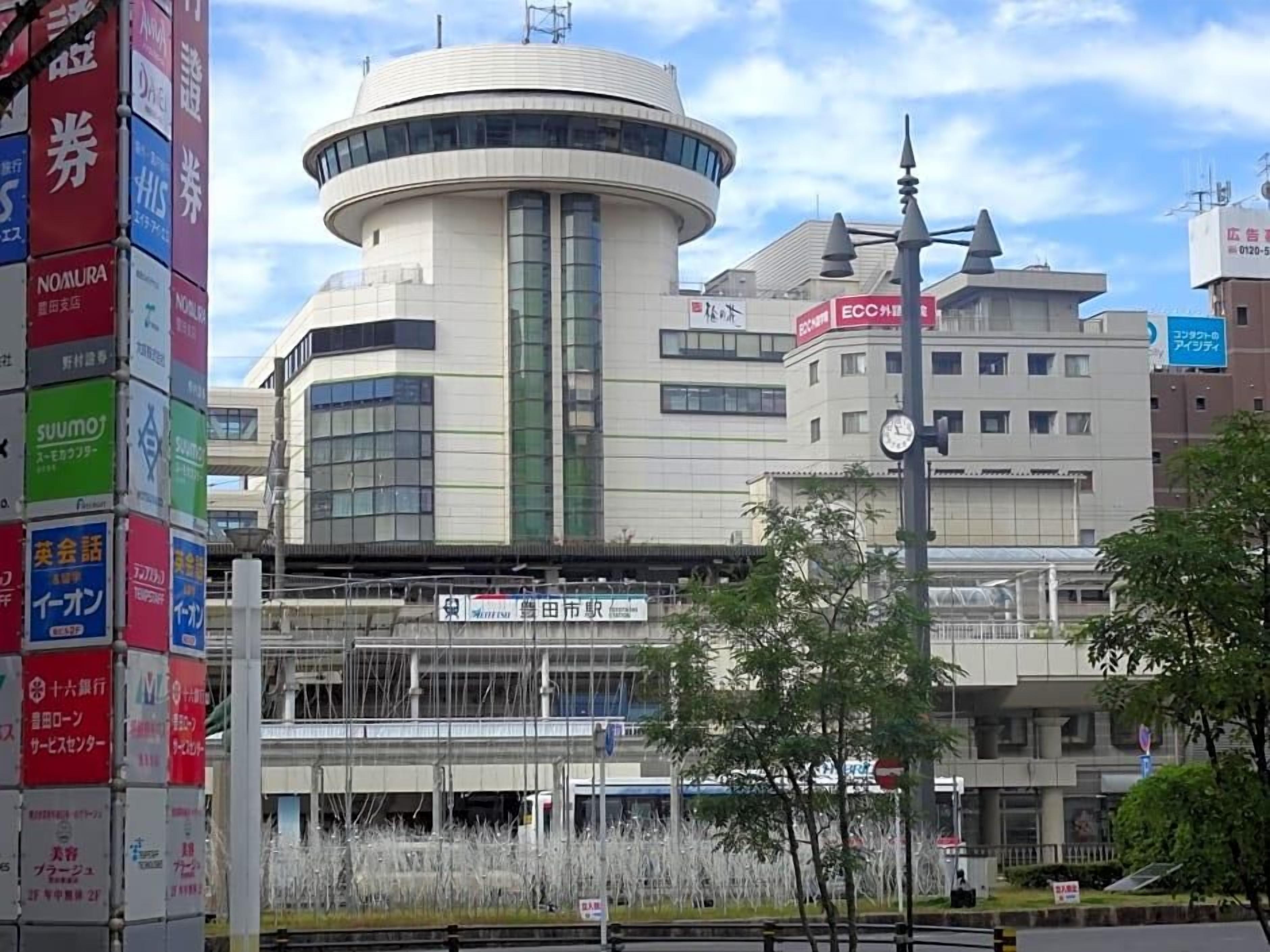 A modern building with a circular central section, surrounded by commercial signage.