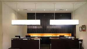 A reception desk with two counters, a dark tiled wall, and a ceiling with recessed lighting. - Hotel Toyota Castle (Toyota)