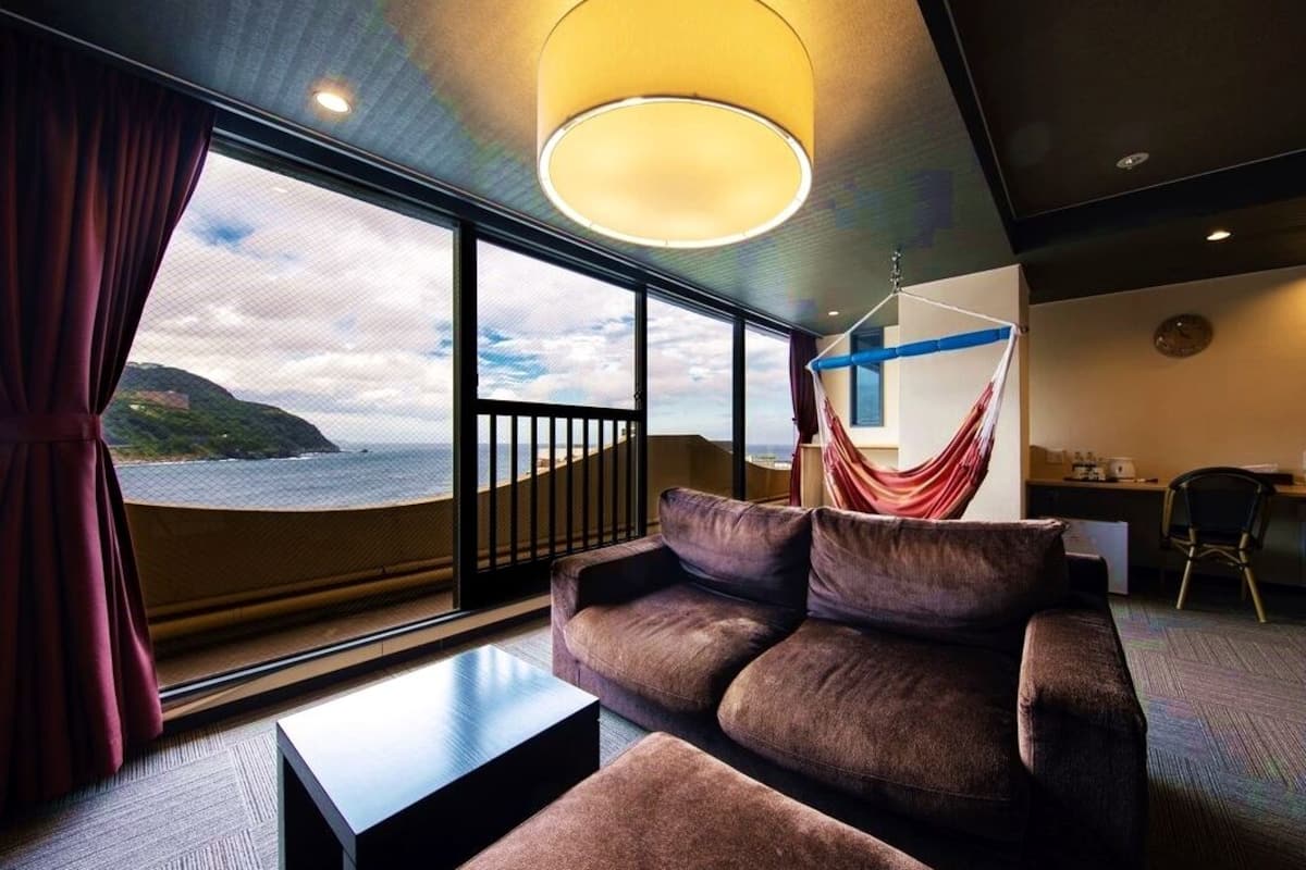 A modern room with a sofa, a coffee table, and a hammock.