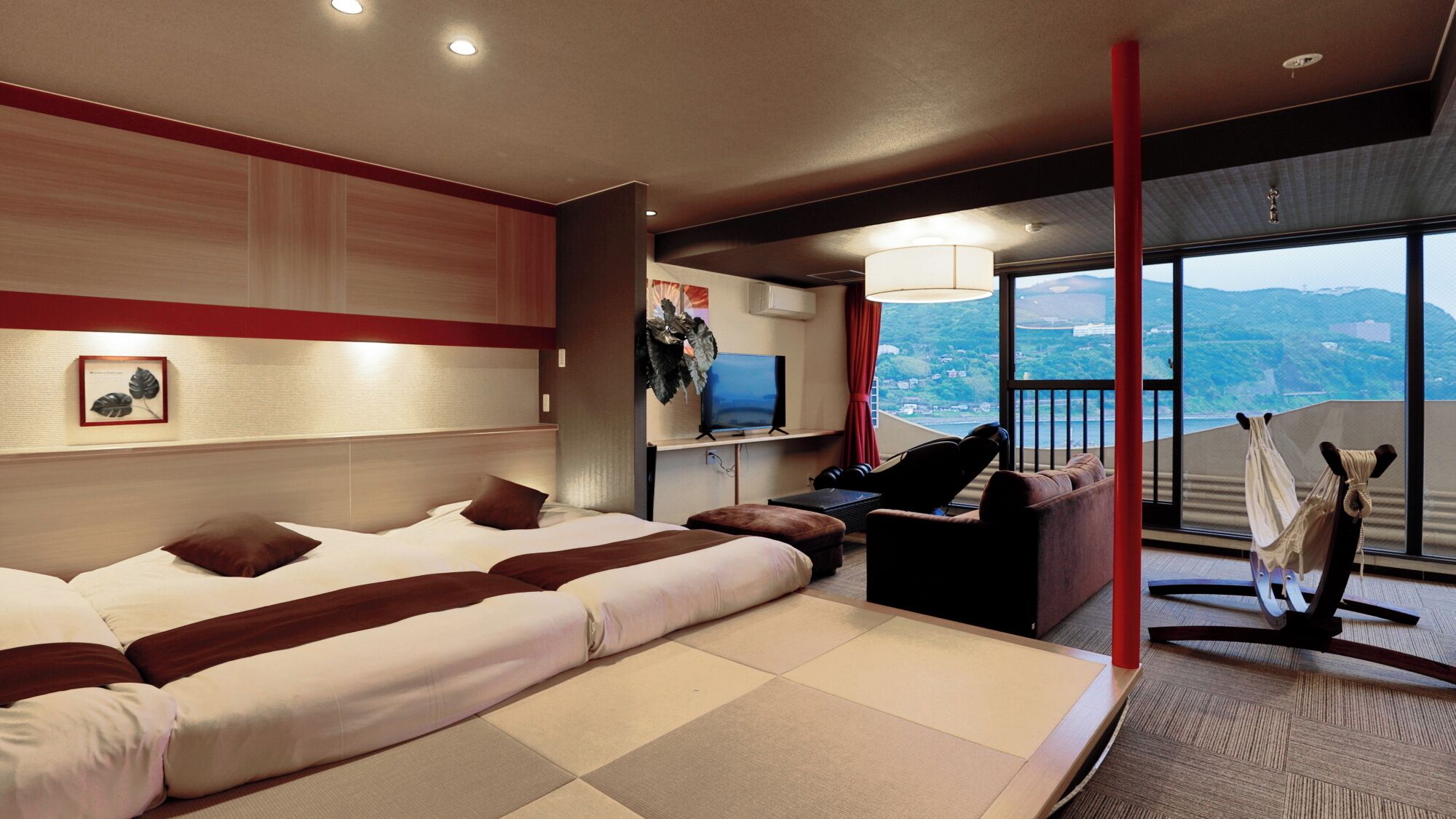 A modern hotel room with a large bed, a desk with a chair, a TV, and a balcony with a view.