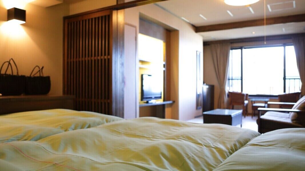 A hotel room with a bed, a desk, a chair, and a window.