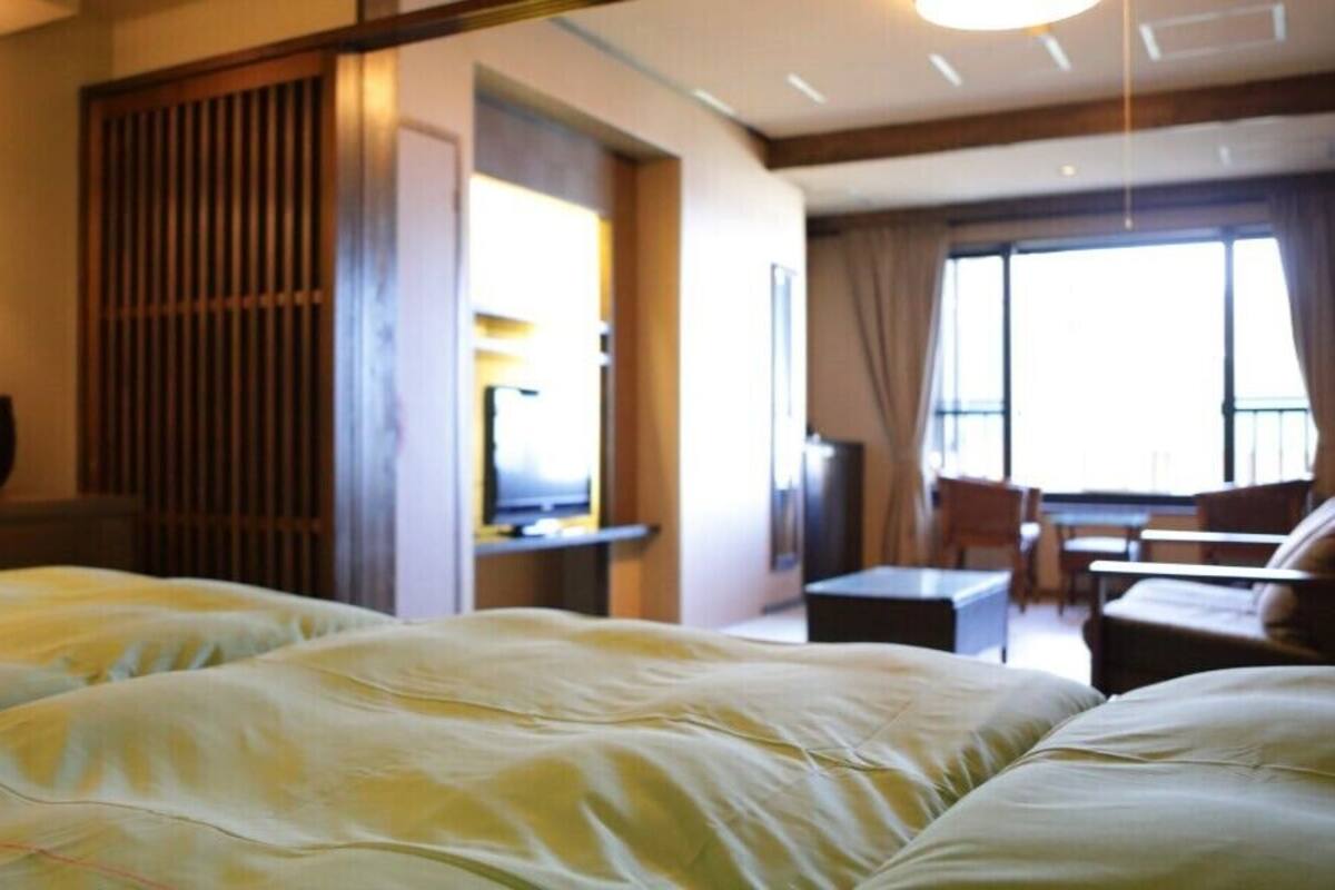 A hotel room with a bed, a desk, a chair, and a window.