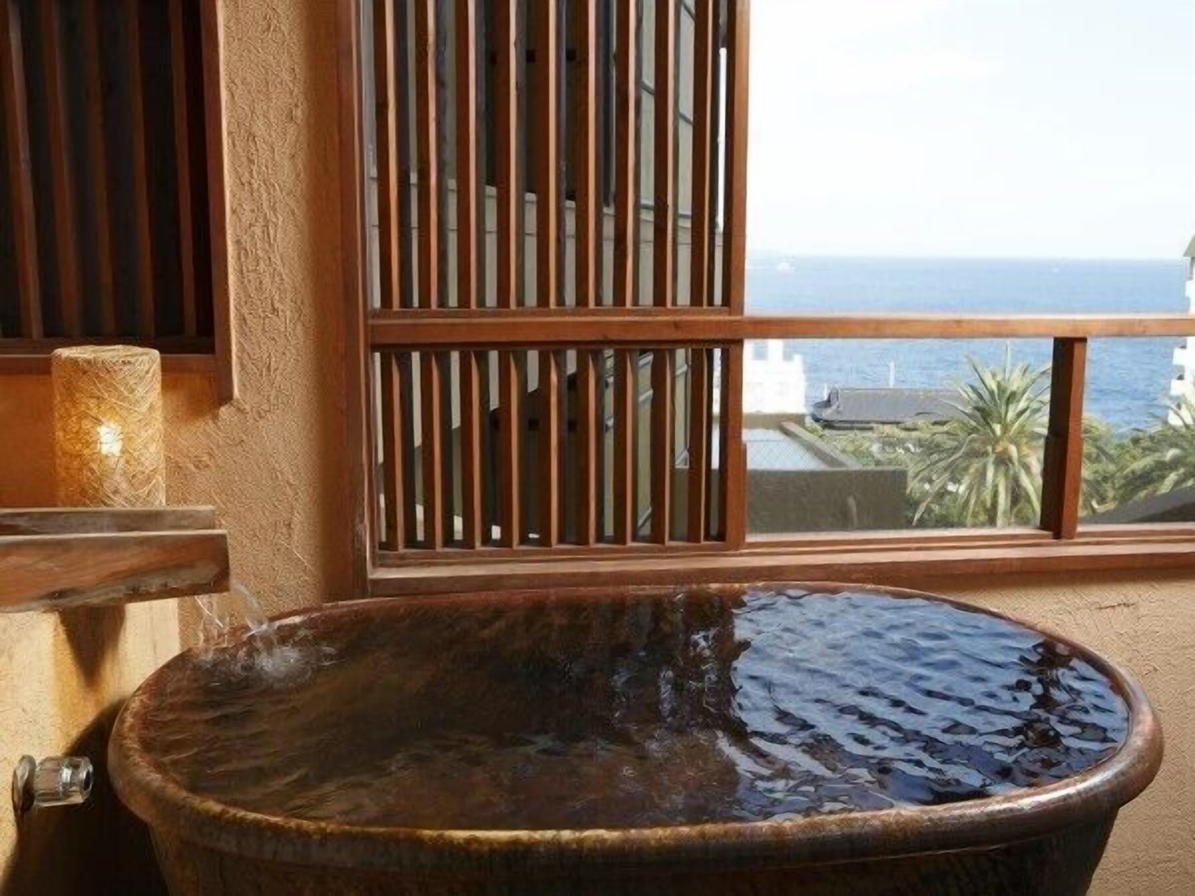 A bathtub with a view of the ocean through a window.
