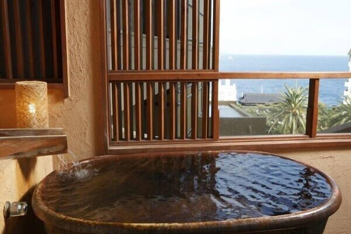 A bathtub with a view of the ocean through a window.