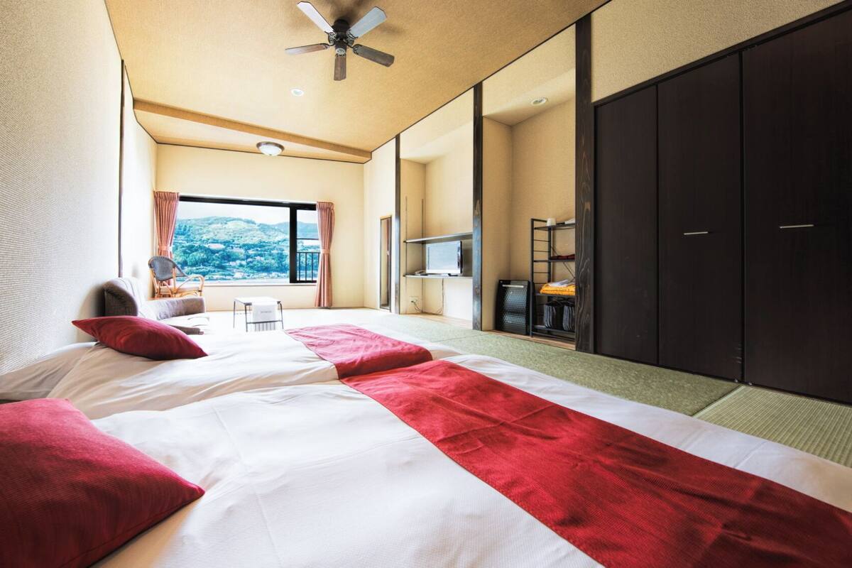A hotel room with a bed, a desk, a chair, a TV, and a wardrobe.