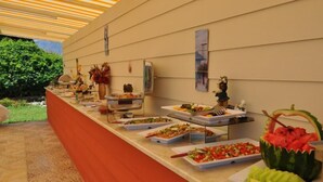 A buffet setup with various food items and a decorative watermelon centerpiece.