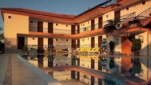 A multi-story hotel with a central courtyard featuring a reflective pool and sun loungers.