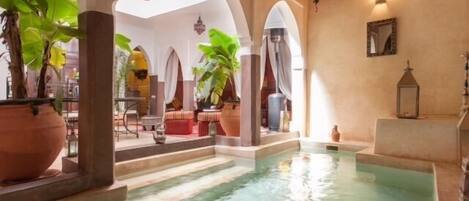 Una piscina techada, sombrillas, sillones reclinables de piscina