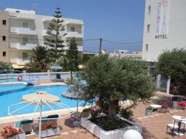 Un hotel con piscina, mobiliario exterior y un árbol grande.