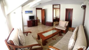 A living room with a sofa, armchairs, a coffee table, a TV, and a cabinet. - Villa Royal View (Ohrid)