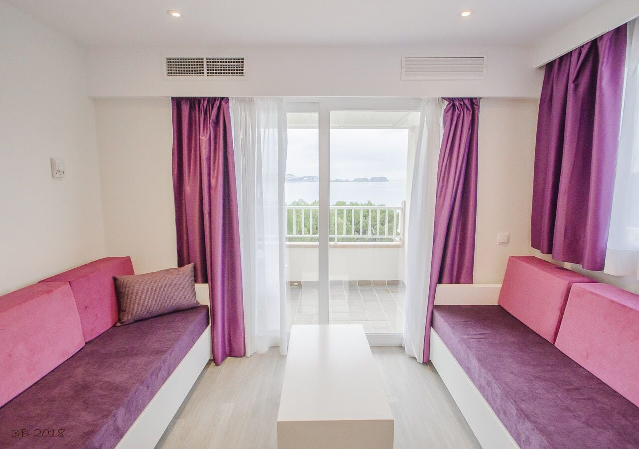 A modern room with a balcony, purple sofas, and a white table.