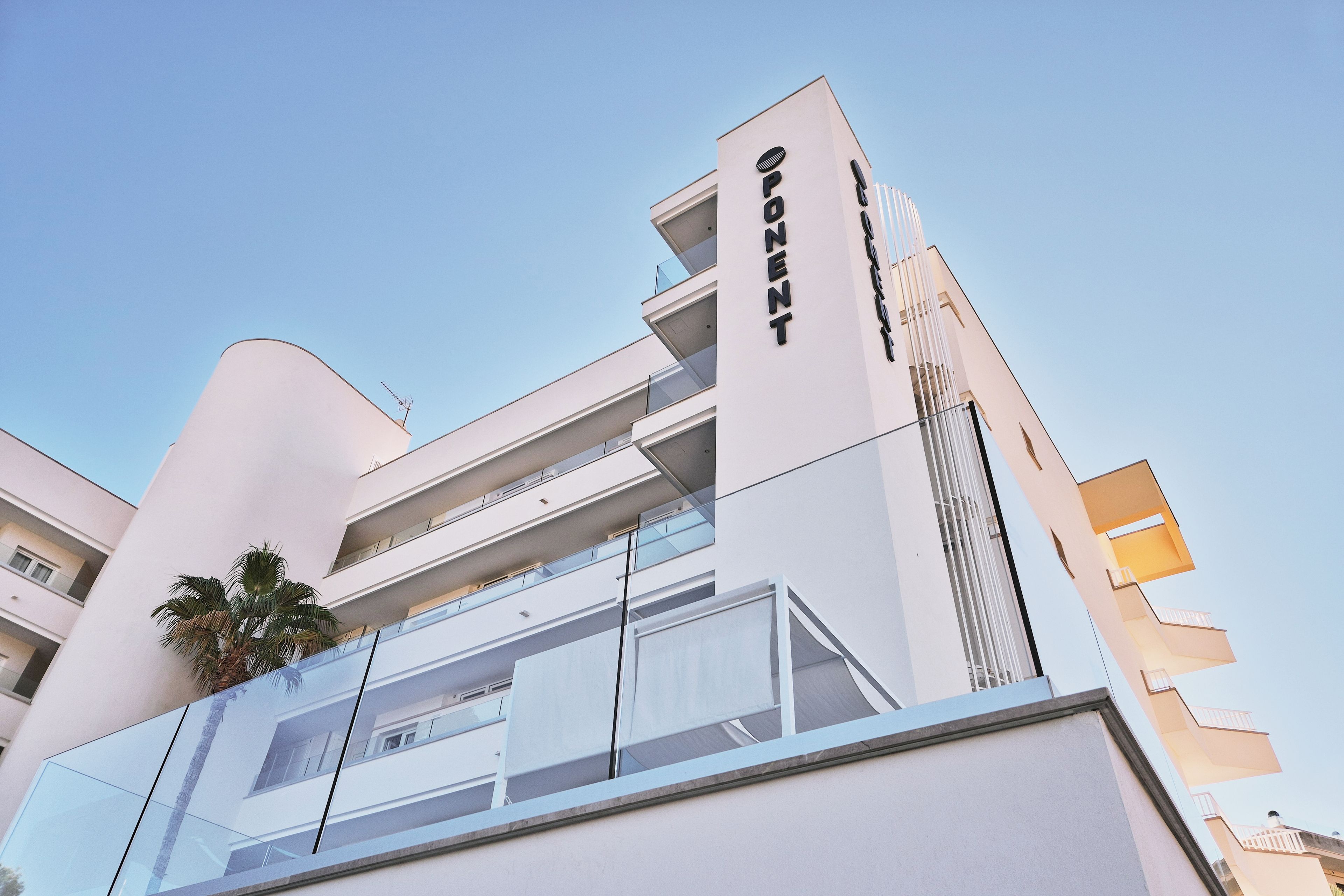 A modern building with a prominent 'OPONENT' sign, large glass windows, and balconies.