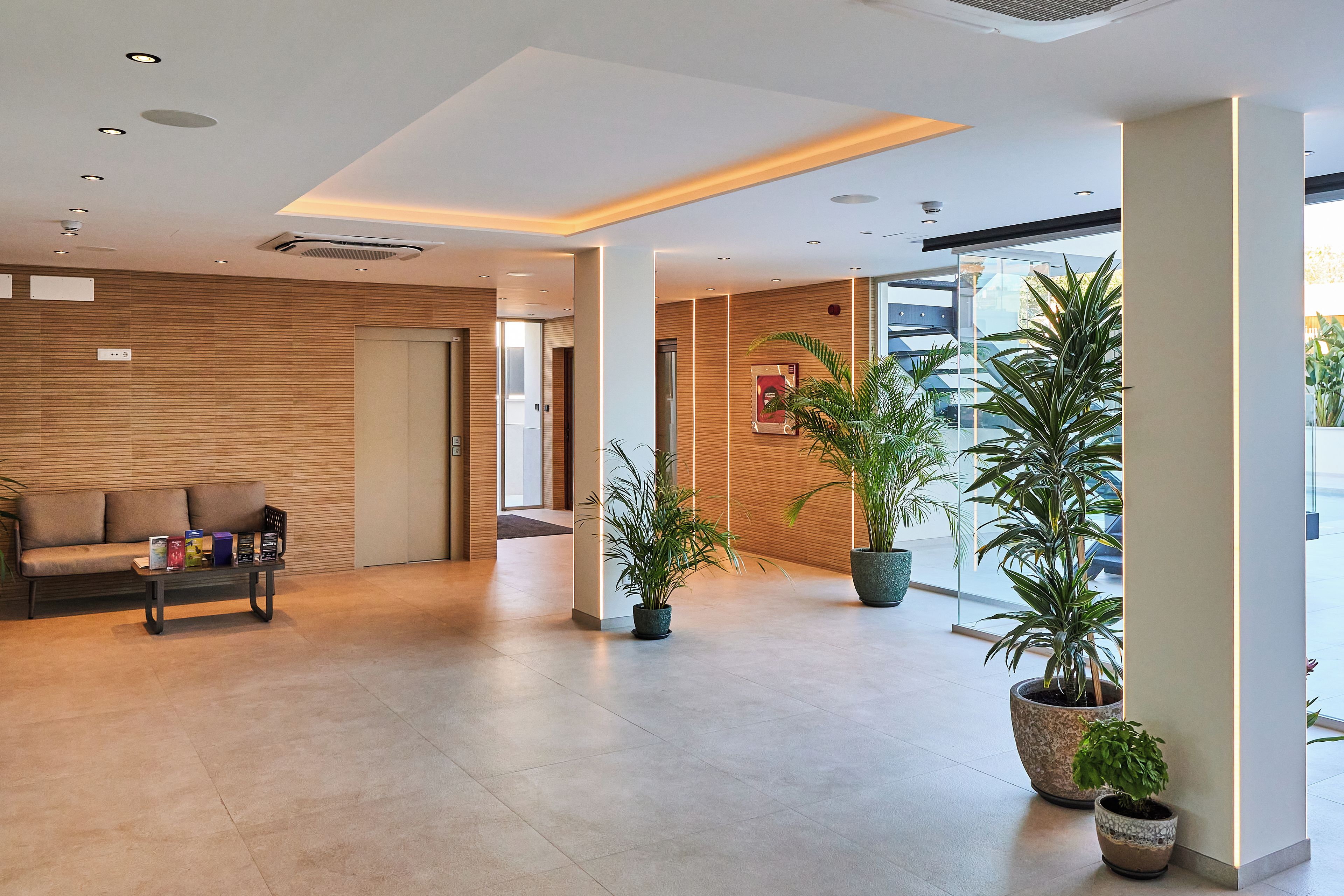A modern lobby with a sofa, a coffee table, and potted plants.
