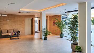 A modern lobby with a sofa, a coffee table, and potted plants.