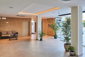 Un hall d’entrée moderne avec un canapé, une table basse et des plantes en pot.