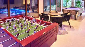 A foosball table in a well-lit indoor space with a pool table and comfortable seating.