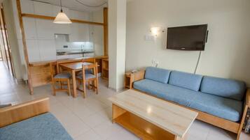 A modern living space with a kitchen, dining area, sofa, and a TV mounted on the wall.
