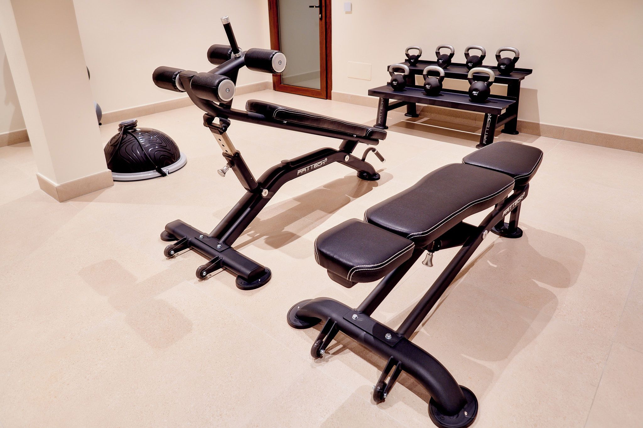 A gym with exercise equipment including a bench, dumbbells, and a kettlebell.
