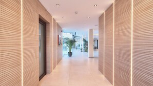 A modern hallway with wooden paneling, recessed lighting, and potted plants. - Apartamentos Ponent (Calvia)