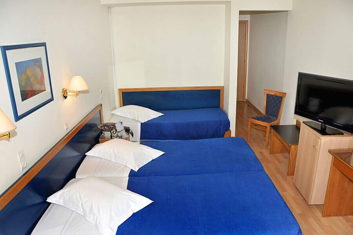 Habitación de hotel con dos camas, televisión, escritorio y una silla.