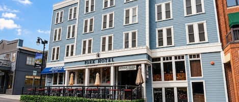 Un edificio de varios pisos con un letrero 'Park Hotel', que cuenta con un restaurante y tiendas en la planta baja.