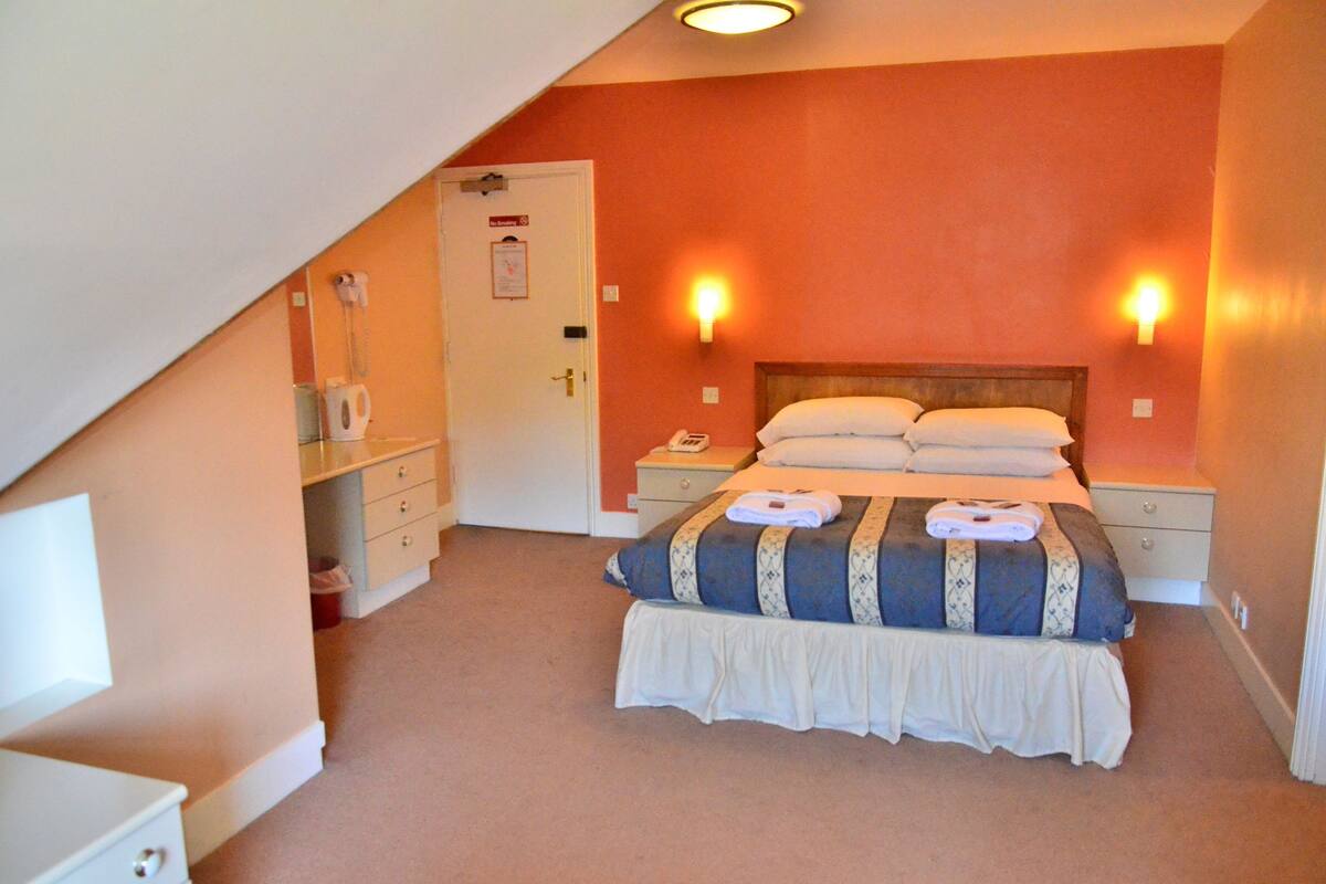 A bedroom with a bed, bedside tables, a nightstand, a dresser, a door, and a ceiling light.