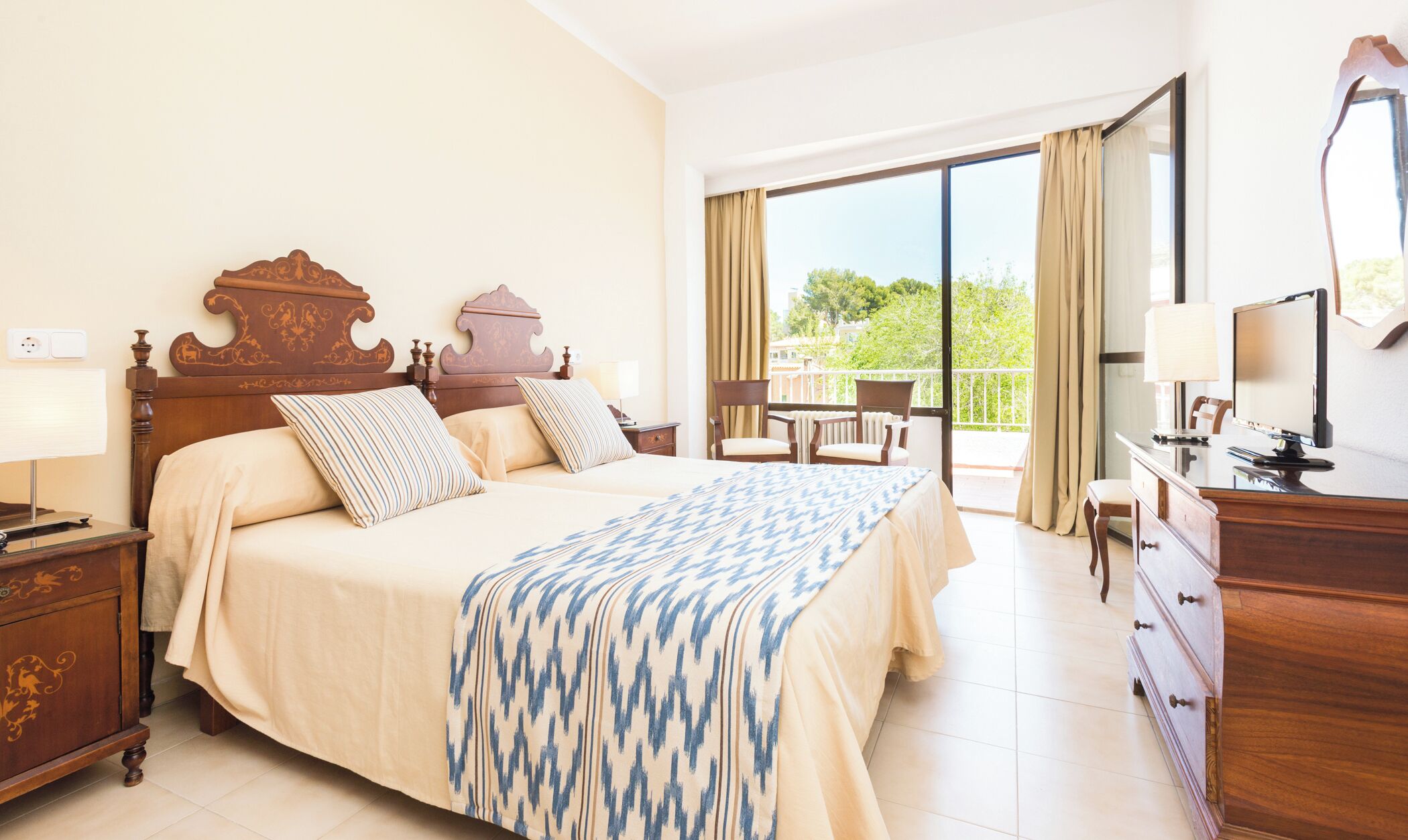 Habitación de hotel con una cama grande, un escritorio con computadora, una silla y un balc ón con vistas.