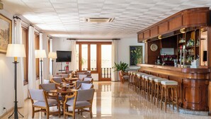 Un hall de hotel con una zona de bar, espacios de asiento y un televisor.
