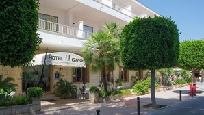 Un hôtel à la façade blanche, doté d’une terrasse et d’un jardin bien entretenu.