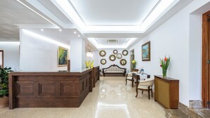 Un hall d’hôtel comprenant un comptoir d’accueil, un espace salon et des miroirs décoratifs sur les murs.