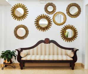 A room with a striped sofa and multiple wall-mounted mirrors with sunburst designs. - Gaya (Calvia)