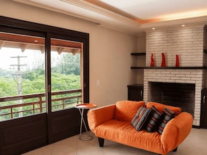 A room with a sofa, a fireplace, and a view through a sliding door. - Guarita Park Hotel By Life Hoteis (Torres)